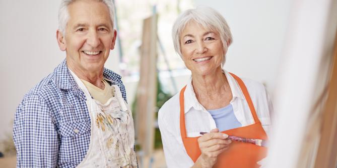 Older couple in smocks on a painting course